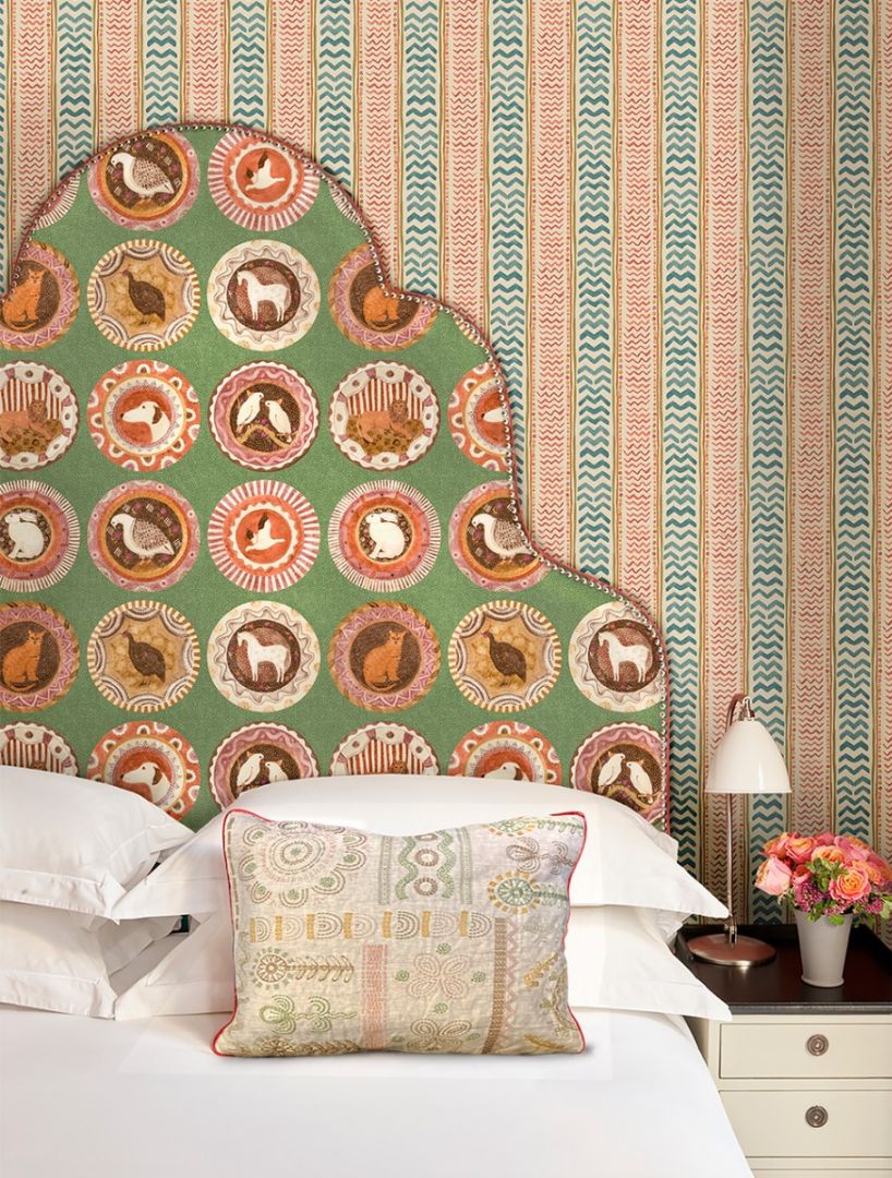 A Kit Kemp bedroom scheme featuring a statement headboard and striped wallpaper